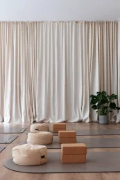 Meditation cushions, mats and cork blocks set up before soft curtains at Energy Studio Vienna