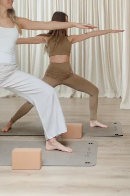A teacher guiding a student through a standing pose at Energy Studio Vienna